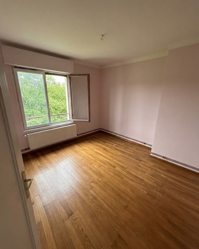 La même chambre après intervention : pièce vide, parquet dégagé et balayé, fenêtre ouverte sur les arbres